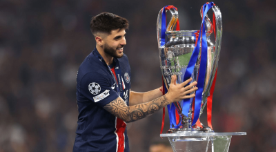 Jogador do Paris Saint-Germain segurando o troféu da Liga dos Campeões da UEFA, cercado por fit...